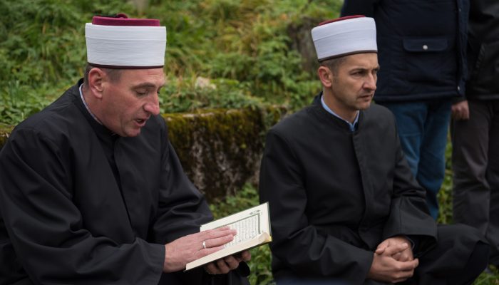 quran holy book reading by imam  on islamic funeral with white thumb stones graweyard background